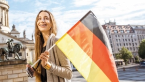 Saksaa oppiva opiskelija kantaen Saksan lippua Yleistä saksasta, Saksan kielen perusteet.
