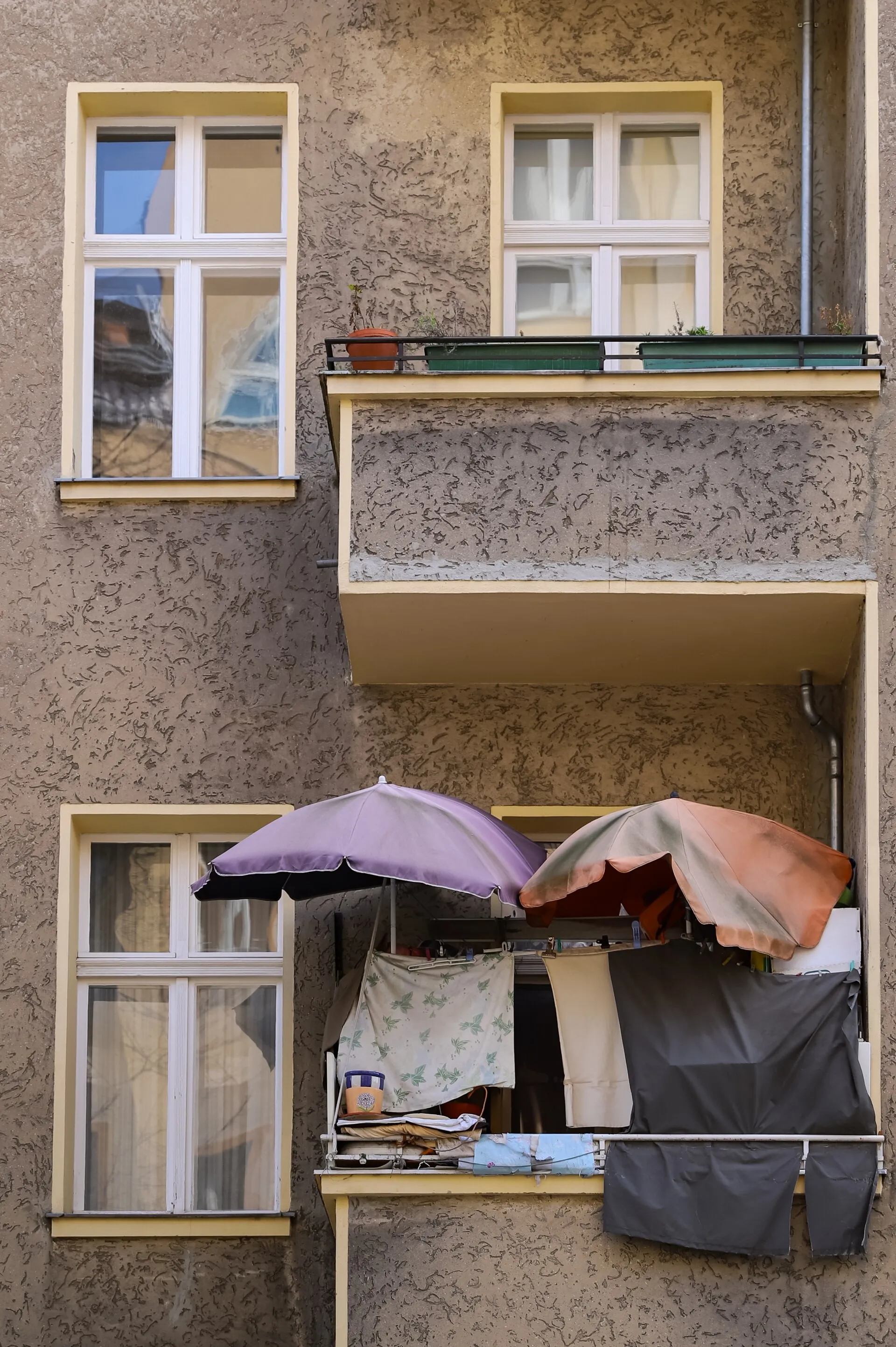 Berlin Kreuzberg'de bir apartman balkonunda güneş şemsiyeleri altında asılı kurutulan çamaşırlar