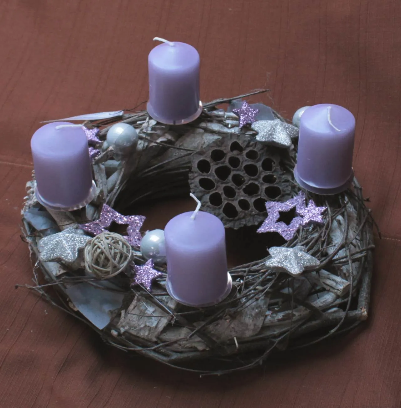 Üzerinde dört mor mum, gümüş ve mor süs yıldızlarıyla süslenmiş geleneksel bir Adventskranz (Advent çelengi)