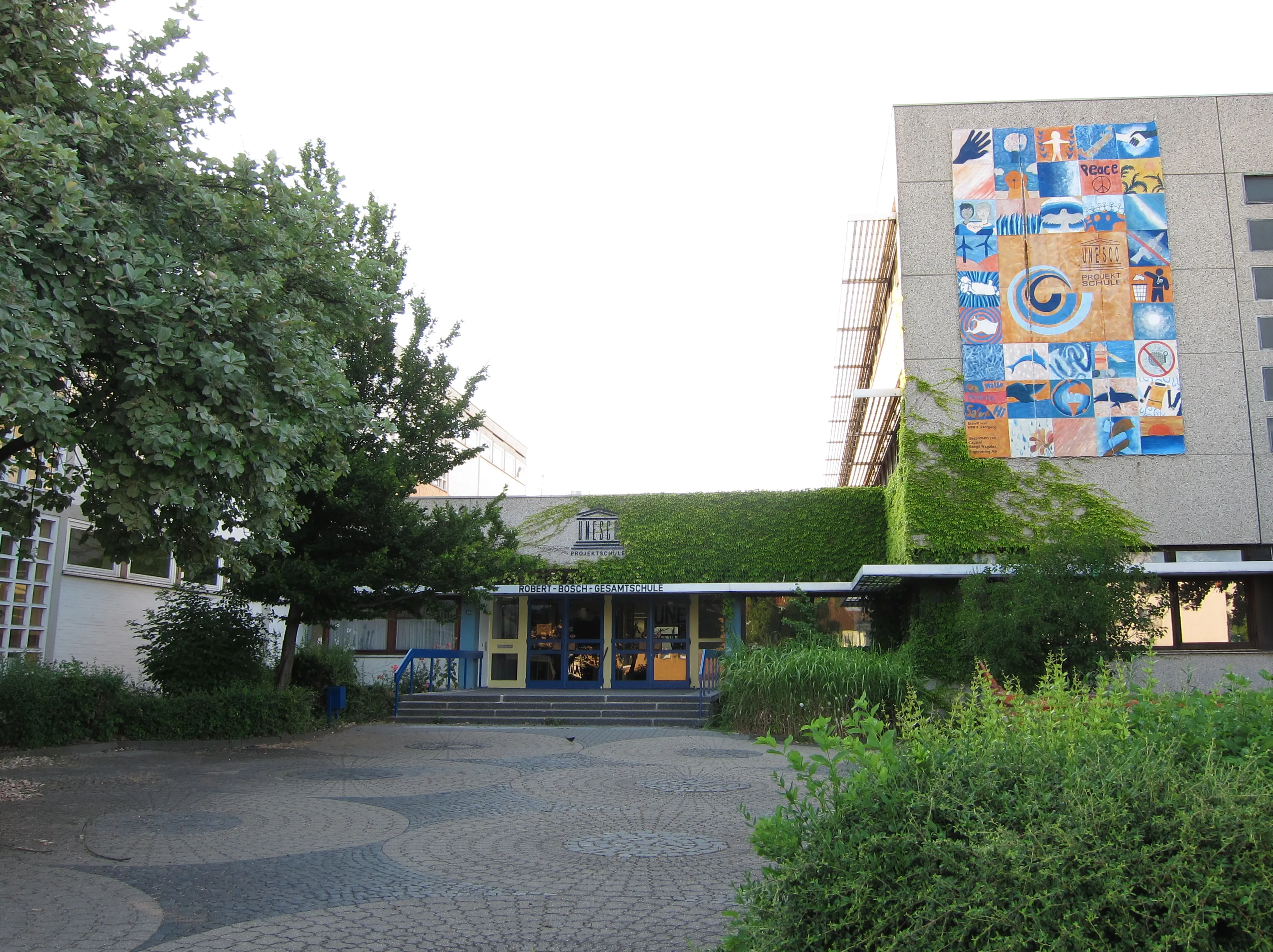Almanya'da bir Gesamtschule'nin (Robert-Bosch-Gesamtschule Hildesheim) giriş cephesi ve UNESCO Projektschule tabelası