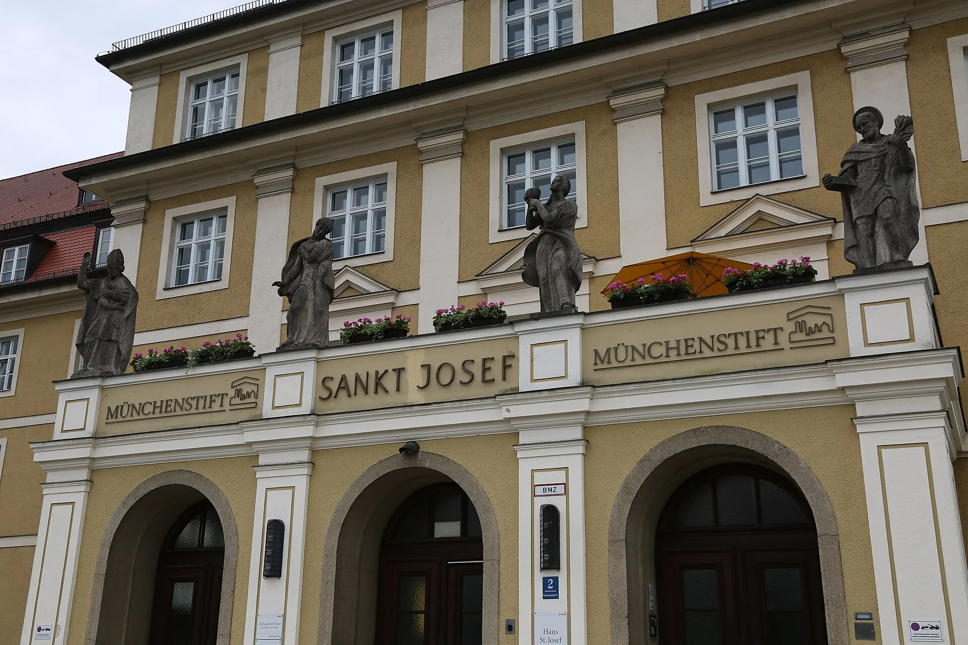 Münih'teki Sankt Josef Pflegeheim binasının heykellerle süslü tarihi cephesi ve 'Münchenstift' tabelası