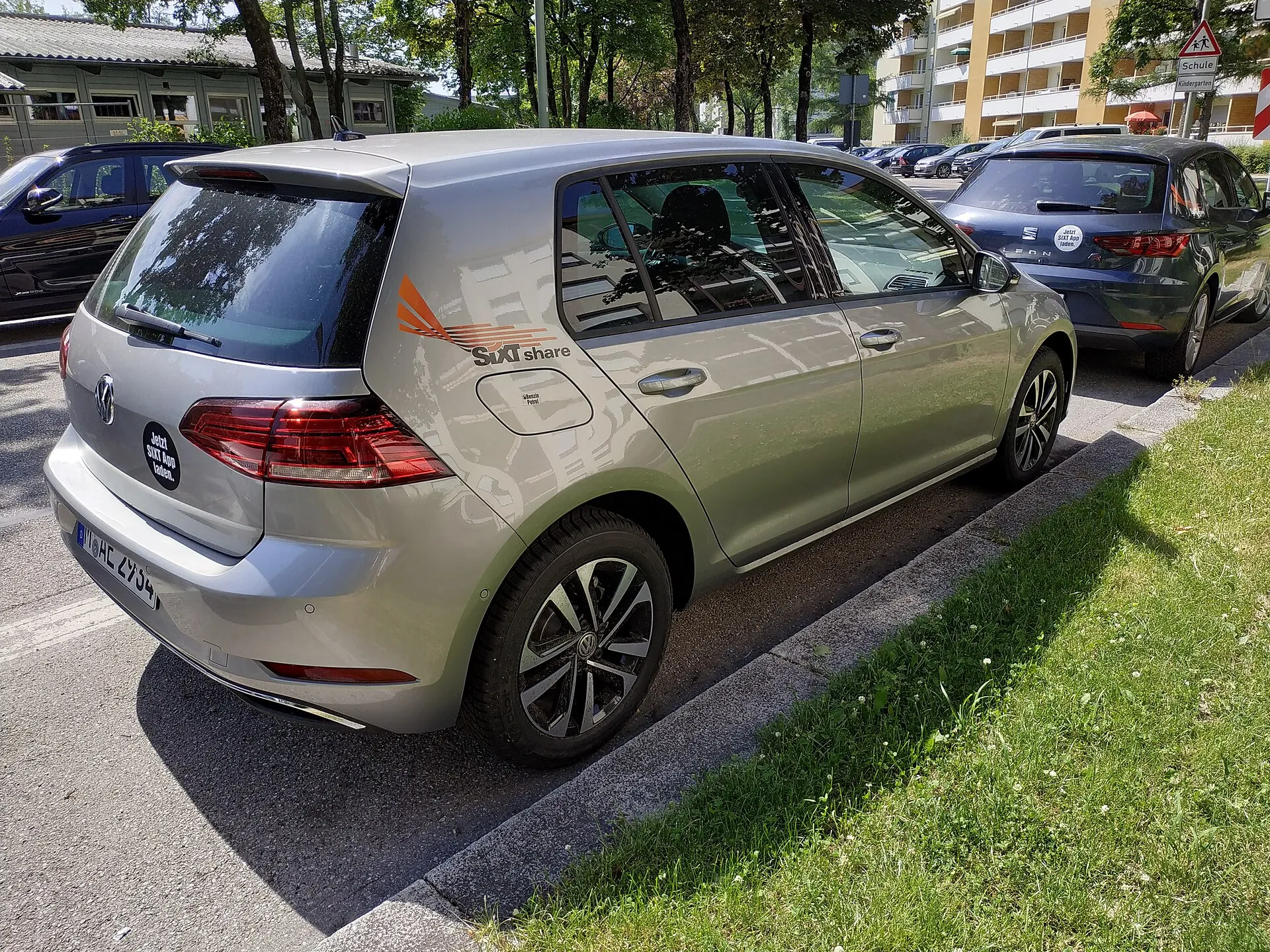 Münih'te bir cadde kenarında park halinde, üzerinde SIXT share logosu bulunan gri renkli bir paylaşımlı kiralık otomobil